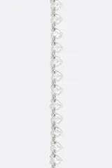 Pulsera de cadena fina dorada de acero inoxidable con una hilera de cristales de vidrio en forma de corazón de múltiples colores. Incluye cierre de mosquetón ajustable y dije de la marca.