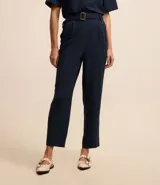Pantalón zanahoria de mujer confeccionado en tela airflow color azul marino, con trabillas en la cintura, cinturón con hebilla, pliegues y elástico en la espalda.