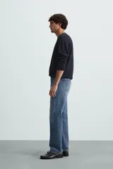 Jersey color crudo de tejido de punto, con cuello redondo y mangas largas. Corte amplio y terminaciones en rib.