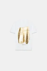 Camiseta de algodón con cuello redondo y manga corta. Presenta un diseño estampado frontal con efecto metalizado plateado sobre fondo rectangular.