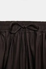 Pantalón de tiro medio con cintura elástica ajustable mediante cordones. Presenta un diseño de pernera abullonada con puños ajustables mediante lazos en los tobillos y bolsillos laterales ocultos en las costuras.