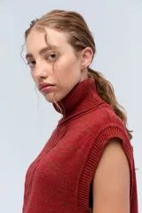 Chaleco de punto azul con cuello alto y diseño de trenzas.