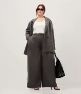 Pantalón de sastrería gris de corte wide leg, con cintura alta, bolsillos laterales y detalles de ajustes con botones en los ruedos.
