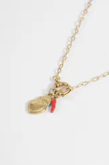 Collar de cadena de eslabones dorados con cierre frontal de argolla y dijes colgantes: un corazón sagrado dorado y un pequeño ají rojo.