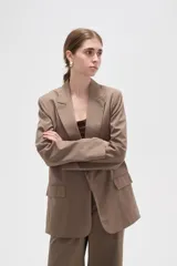 Blazer de corte holgado con diseño de rayas verticales, cuello solapa y cierre frontal con un botón. Presenta bolsillos laterales con solapa y mangas largas.