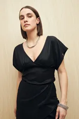 Top negro de tejido acanalado con acabado brillante, escote en V profundo, manga corta y frunce bajo el busto.