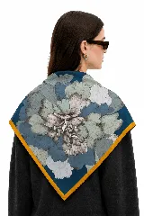 Pañuelo cuadrado con estampado floral central en tonos azules, verdes y gris, con borde en color mostaza.