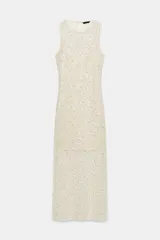 Vestido midi de cuello redondo y sin mangas, confeccionado en tejido de red con lentejuelas brillantes. Presenta un diseño con forro interior corto, aberturas laterales en el bajo y cierre de botón en la espalda.