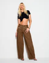 Jean wide leg color marrón, con tiro medio y aplicación de strass en toda la prenda, de corte relajado con bolsillos delanteros y traseros.