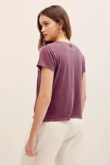 Remera de algodón color morado, con mangas cortas, cuello redondo y bordado de cuentas y pedrería en la parte frontal.