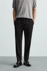 Pantalón regular fit color negro de tejido con viscosa, con cintura elástica ajustable con cordón, bolsillos frontales y traseros.
