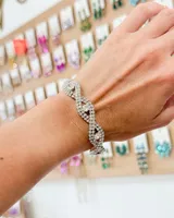 Pulsera de diseño entrelazado con múltiples hileras de cristales brillantes y piedras centrales de mayor tamaño.