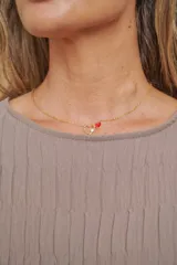 Cadena dorada con dos dijes de corazón: uno calado con una piedra brillante en el centro y otro más pequeño de color rojo liso.