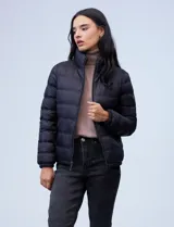 Campera de plumas reversible marca Michael Kors. Un lado es liso y el otro estampado con el logo de la marca. Tiene abertura central con cierre metálico, bolsillos delanteros y avíos metálicos con el logo. Incluye bolsa autoportante.