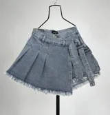 Short pollera de jean celeste con diseño asimétrico, tablas y detalle de cintas laterales.