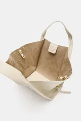 Bolso bandolera de formato city color marrón, con diseño estructurado, pespuntes decorativos, doble asa de mano y cremalleras laterales con tiradores colgantes.