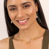 Collar dorado con cadena fina y dijes colgantes de perlas barrocas y piezas irregulares con textura.