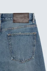 Jeans de mezclilla de algodón, tiro medio, con pierna recta y ajuste ligeramente holgado. Presenta efecto lavado y cierre frontal de botonadura.