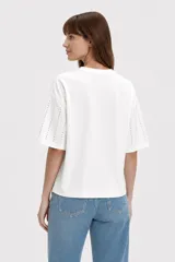 Remera negra de algodón con cuello redondo, mangas cortas y diseño holgado, decorada con líneas verticales de strass.