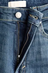 Jean de cinco bolsillos en denim de algodón con liviano stretch para una comodidad óptima, de corte ajustado en cintura y cadera, pierna bootcut y tiro alto con cierre y botón.