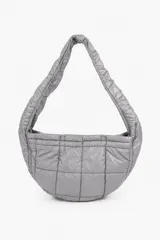 Bolso tipo hobo gris, acolchado con diseño capitoné de cuadros, correa de hombro integrada y cierre superior con broches a presión.