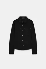 Camisa negra entallada con cuello clásico, manga larga y cierre frontal con botones a presión dorados. Presenta dos bolsillos de plastrón en el delantero, cada uno con un botón a presión dorado.