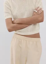 Chaleco de punto fino calado color beige, con cuello redondo y mangas cortas.
