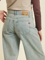 Jean de denim en corte balloon fit, con tiro medio y lavado claro. Presenta costuras laterales curvadas que definen su silueta amplia y relajada.