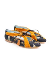 Zapato tipo blucher de raso negro con bordado de libélulas en color ocre. Presenta detalles en terciopelo ocre en los laterales y el talón, con un borde festoneado y costuras en zigzag. Se ajusta con cordones de algodón rematados con borlas de ante.