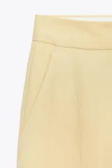 Pantalón de vestir amarillo pálido, de tiro alto, corte recto y largo a la altura del tobillo.
