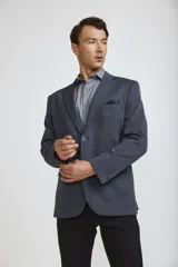 Blazer de corte clásico color azul oscuro, con cierre frontal de un botón, solapas de muesca y bolsillos laterales con solapa. Presenta un bolsillo superior con pañuelo decorativo y puños con botones.