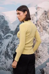 Polera de tejido de punto fino color blanco, con cuello alto, mangas largas y terminaciones con detalle de ondas en puños, cuello y ruedo.