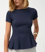 Blusa de corte peplum confeccionada en tejido Punto Roma, con escote redondo, mangas cortas y recortes estructurados que definen la silueta.