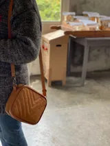 Bandolera color naranja de cuero con diseño capitoneado en forma de V.