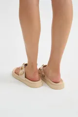 Ojotas de dedo negras con suela plana y gruesa, decoradas con apliques metálicos de piedras de colores en la tira.