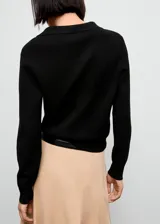 Jersey de punto fino color negro, con cuello en pico y solapa tipo polo, de manga larga y diseño recto.