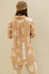 Camisa de manga larga color beige con estampado blanco de estilo étnico, corte oversize y cierre frontal con botones.