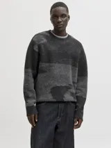 Sweater de punto con diseño de bloques de color en tonos grises y negros, manga larga, cuello redondo y ajuste relajado. Presenta puños y cuello acanalados con una textura suave y elástica.