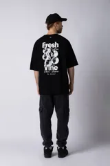 Remera de corte oversize color negro, con cuello redondo y mangas cortas. Presenta una estampa pequeña en el centro del pecho con la frase 'Fresh from the vine' en tipografía blanca.