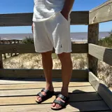 Short de tejido de punto con textura, color blanco, con bolsillos laterales y logo pequeño bordado en la pierna.
