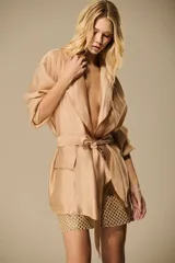 Blazer de organza color blanco marfil, con solapas clásicas, bolsillos frontales aplicados, mangas largas y faja del mismo material para ajustar en la cintura.