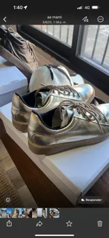 Zapatillas urbanas de cuero color marrón, con suela blanca cosida y detalle de talón en tono metalizado dorado. Presentan cordones al tono y ojales metálicos.