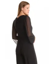 Enterito negro de seda fría con escote en V cruzado, mangas largas voluminosas de gasa transparente con puños elásticos fruncidos. Tiene cintura elástica interna, lazo lateral ajustable y pierna de corte recto al tobillo.