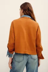 Campera tostado de estilo utilitario, con cuello alto, cierre frontal y bolsillos frontales con solapa. Presenta mangas largas con presillas.