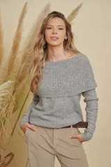 Buzo de tejido de punto color gris, con diseño de cuello amplio que permite usarlo con los hombros descubiertos o como cuello tipo buche. Presenta mangas largas y un calce holgado.