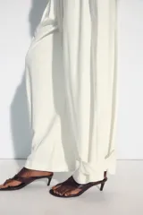 Pantalón fluido de tiro medio, color blanco, con cintura elástica ajustable con cordones, bolsillos laterales y bajo ajustable con trabilla y botón a presión.