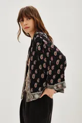 Kimono corto de estilo bohemio, confeccionado en viscosa negra con estampado paisley y detalles bordados en los bordes frontales y mangas. Presenta mangas tres cuartos y un lazo ajustable en la cintura con estampado animal print.