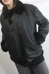 Campera bomber de napalán de cuero genuino en color negro, con interior y detalles en cuello y puños de piel sintética negra. Cuenta con cierre frontal metálico y bolsillos laterales.