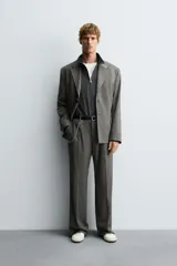 Pantalón de vestir con corte flare y ajuste relajado, confeccionado en tejido con viscosa y patrón de espiga. Cuenta con bolsillos frontales, bolsillos traseros de vivo y cierre frontal con cremallera y botón.