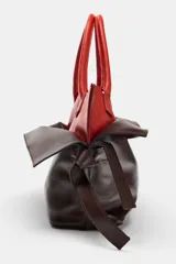 Bolso alargado de piel con doble asa de mano, diseño de doble solapa en combinación de colores y detalle de nudo en los laterales.